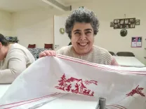 Erika happily shows her handmade embroidered to the camera.