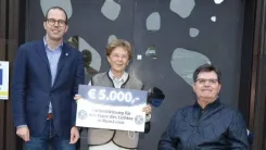 Tünde hält einen Scheck über 5.000 € in ihren Händen, umgeben von zwei Männern vom Bischof Stecher Gedächtnisverein und dem Kiwanis Club Schwaz.